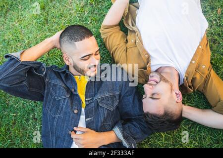 Couple gay allongé sur l'herbe au parc. Banque D'Images