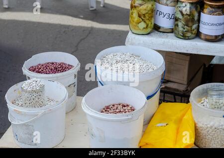 Différentes variétés de haricots secs sur le comptoir du marché local. Champignons sauvages en conserve en arrière-plan. Vente de rue. Foire agricole de printemps. Po Banque D'Images