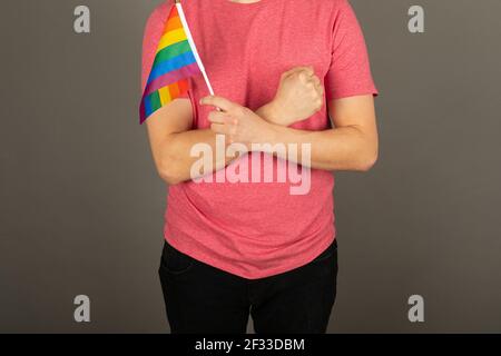 Homme gay portant un t-shirt rose et un drapeau arc-en-ciel Banque D'Images