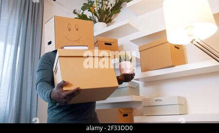 Homme noir excité avec boîte à carboard au-dessus de sa tête, s'installant dans une nouvelle maison. Photo de haute qualité Banque D'Images