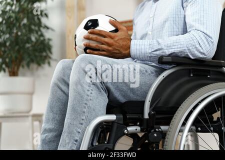 Homme invalide ou handicapé assis sur un fauteuil roulant et tenant le football bille Banque D'Images