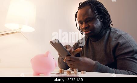 Homme noir afro-américain effectuant des achats en ligne à l'aide d'une carte de crédit et d'une application pour smartphone. Photo de haute qualité Banque D'Images