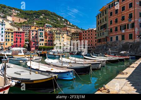 Les bateaux amarrés dans le petit port comme vieilles maisons colorées en arrière-plan dans la ville de Camogli, Ligurie, Italie. Banque D'Images