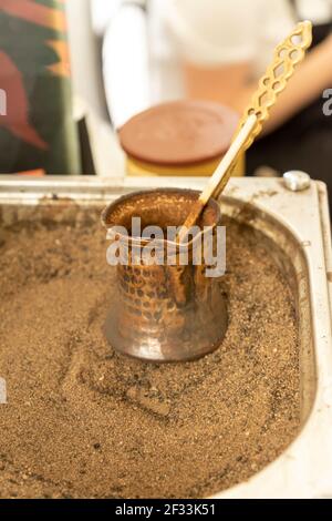 Café turc préparé sur du sable chaud pour un goût et un arôme uniques. Boisson orientale traditionnelle dans la cezve de cuivre. Banque D'Images