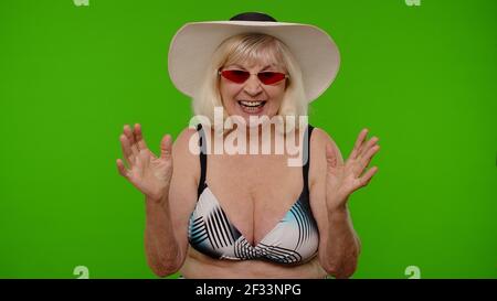 Femme touriste senior levant la main dans le geste victorieux, dansant, célébrant le succès, profitant de la chance Banque D'Images