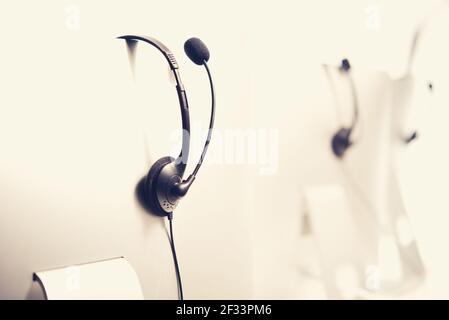 Micro-casques suspendus sur les moniteurs d'ordinateur dans le centre d'appels, effet de tonalité vintage Banque D'Images