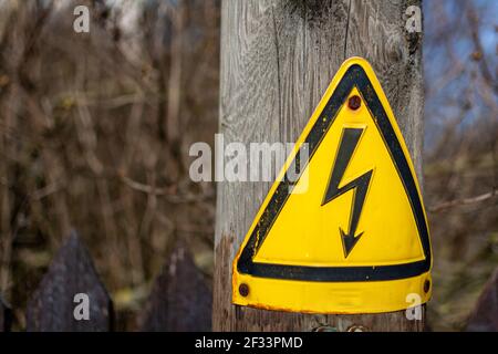 Panneau au bas d'un poteau électrique en bois d'avertissement du danger d'électrocution si une tentative est faite pour monter le poteau à côté d'une rue. Banque D'Images