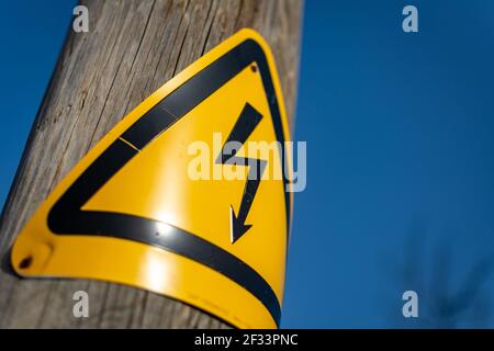 Panneau au bas d'un poteau électrique en bois d'avertissement du danger d'électrocution si une tentative est faite pour monter le poteau à côté d'une rue. Banque D'Images