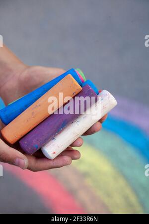Craies. Grands crayons multicolores dans les mains des enfants. L'enfant tient la craie. Dessinez sur la rue. Dessin fascinant pour les enfants. Copier l'espace. Banque D'Images