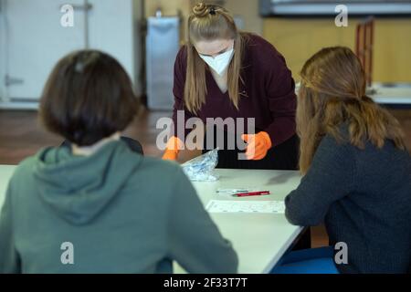 Bergisch Gladbach, Allemagne. 15 mars 2021. Anna Niederau (M), enseignante stagiaire à l'école municipale intégrée de Paffrath, remet des tests rapides Corona aux élèves le matin avant le début des cours. Malgré la hausse des taux d'infection, tous les élèves de la Rhénanie-du-Nord-Westphalie doivent retourner dans les salles de classe, au moins pour une journée. À Bergisch-Gladbach, la distribution des tests de spit aux élèves commence déjà un jour avant les autres écoles. Credit: Federico Gambarini/dpa/Alay Live News Banque D'Images