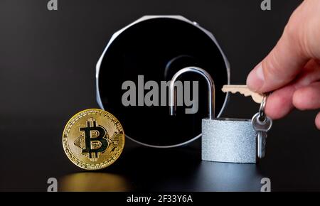 Un Bitcoin et un verrou devant un portefeuille matériel de crypto-monnaie . Banque D'Images