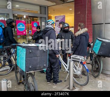 Un groupe de riders travaillant pour la compagnie de livraison de nourriture en ligne Deliveroo attendant les ordres de livraison aux maisons de clients. Banque D'Images