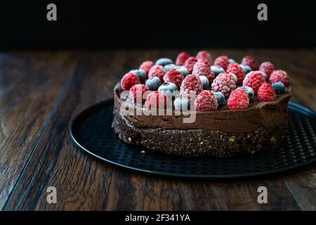 Gâteau cru au chocolat végétalien sans gluten avec framboises et bleuets. Prêt à manger. Banque D'Images
