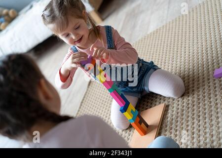 Enfants jouant avec des blocs de bois sur le sol dans leur chambre. Banque D'Images