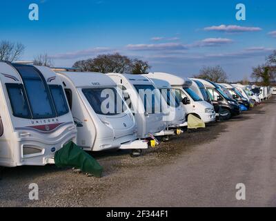 Une rangée de caravanes blanches sur la résistance dans un garage sécurisé de caravane lors d'une journée ensoleillée en hiver avec un ciel bleu. Banque D'Images