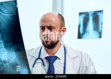 Médecin sérieux étudiant une radiographie d'un patient. Banque D'Images