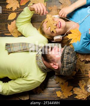 Devinez sa chanson préférée. Homme barbu visage rêveur et femme écoutant la musique casque posé sur fond de bois vue de dessus. Date d'automne agréable confortable Banque D'Images