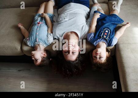 une jeune mère et deux jeunes filles sont allongées le canapé à l'envers Banque D'Images