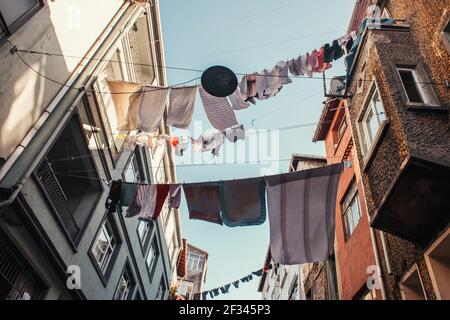 Vue à angle bas des vêtements avec buanderie entre les maisons sur la rue étroite dans le quartier de Balat, Istanbul, Turquie Banque D'Images