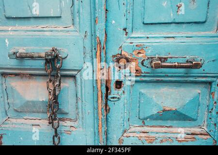 vieilles portes en bois, avec peinture bleue craquelée, poignées métalliques rouillées et chaîne Banque D'Images