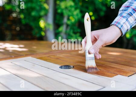 jeune femme peint en bois exotique table en bois dans le jardin avec une brosse - faible profondeur de champ Banque D'Images