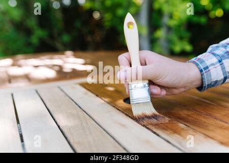 jeune femme peint en bois exotique table en bois dans le jardin avec une brosse - faible profondeur de champ Banque D'Images