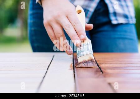 jeune femme peint en bois exotique table en bois dans le jardin avec une brosse - faible profondeur de champ Banque D'Images