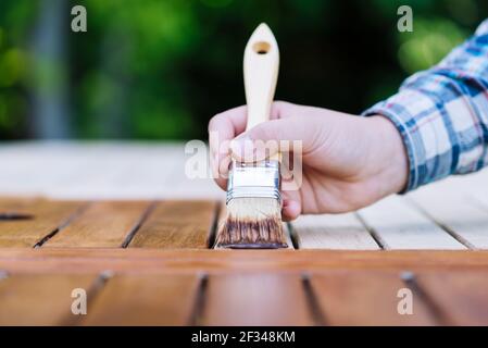 jeune femme peint en bois exotique table en bois dans le jardin avec une brosse - faible profondeur de champ Banque D'Images