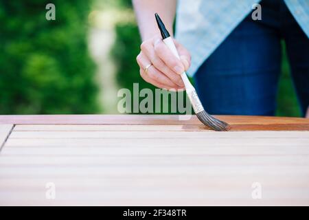 jeune femme peint en bois exotique table en bois dans le jardin avec une brosse - faible profondeur de champ Banque D'Images