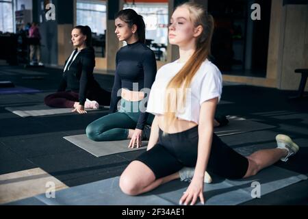 Groupe de jeunes femmes focalisées pratiquant des poses de yoga Banque D'Images