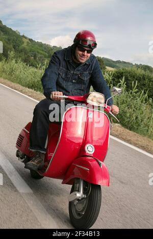 Homme en scooter rouge dans la campagne toscane Banque D'Images