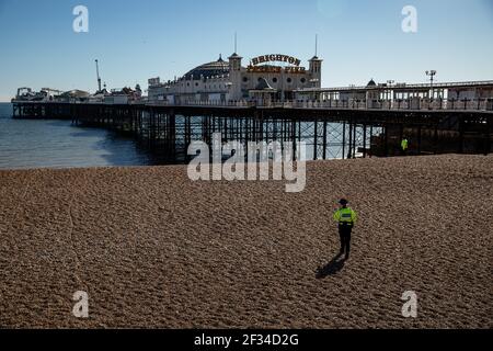 Un membre de l'agent de soutien communautaire de la police patrouilant sur la plage de Brighton car le temps est ensoleillé et clair Banque D'Images