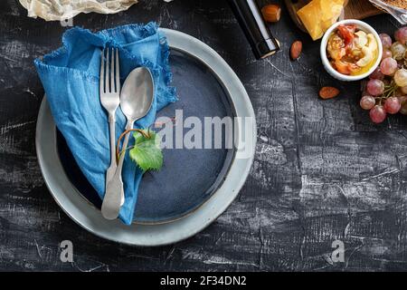 Vider la assiette bleue de service avec une cuillère à fourchette dans le cadre des ingrédients alimentaires cuisine méditerranéenne gastronomie hors-d'œuvre snacks raisins fromage vin. Assiette bleue Banque D'Images