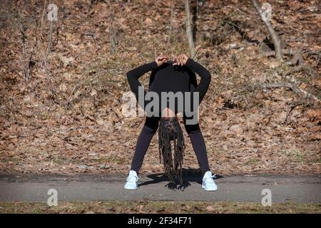 Une femme agile et flexible de la cinquantaine mène un cours quotidien de yoga méditatif dans un parc de Queens, New York. Banque D'Images