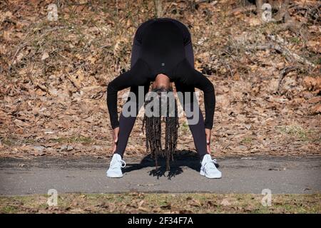 Une femme agile et flexible de la cinquantaine mène un cours quotidien de yoga méditatif dans un parc de Queens, New York. Banque D'Images