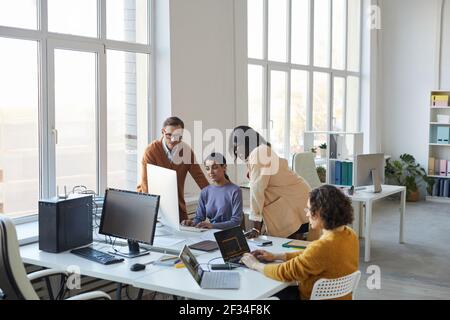 Vue d'ensemble de différentes équipes de développeurs de logiciels utilisant des ordinateurs dans les bureaux modernes, avec l'accent sur les chefs de projet supervisant la production, copie s. Banque D'Images
