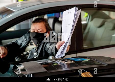 ROTTERDAM, PAYS-BAS - MARS 15: Une femme est vue couler son vote assis dans sa voiture dans une voiture spécialement installée par le bureau de vote le 15 mars 2021 à Rotterdam, pays-Bas lors de l'élection générale des pays-Bas 2021. Les bureaux de vote ont déjà ouvert lundi pour donner aux personnes âgées et aux groupes vulnérables l'occasion d'éviter la foule d'électeurs le mercredi soir. (Photo de Niels Wenstedt/BSR Agency/Alay Live News) Banque D'Images