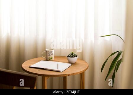 Espace de travail minimaliste à la maison, avec une tasse de café et un carnet blanc ouvert sur le bureau Banque D'Images