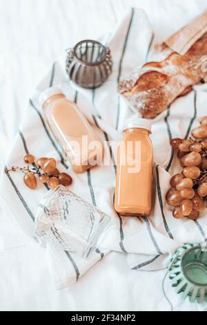 Jus de légumes naturels en bouteilles de plastique, raisins et baguette sur une serviette. Concept pique-nique. Banque D'Images