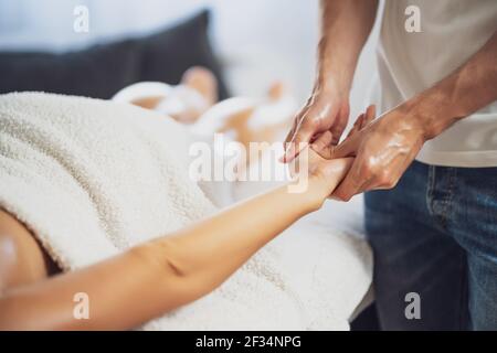 Masseur professionnel faisant un massage thérapeutique. Femme profitant d'un massage dans sa maison. Jeune femme se relaxant massage corporel. Banque D'Images