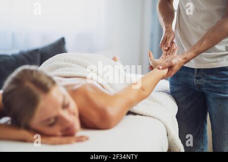 Masseur professionnel faisant un massage thérapeutique. Femme profitant d'un massage dans sa maison. Jeune femme se relaxant massage corporel. Banque D'Images