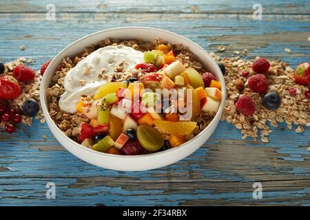 Grand angle de bol de muesli servi sur une table en bois avec divers fruits et baies pour un petit déjeuner sain et nutritif Banque D'Images