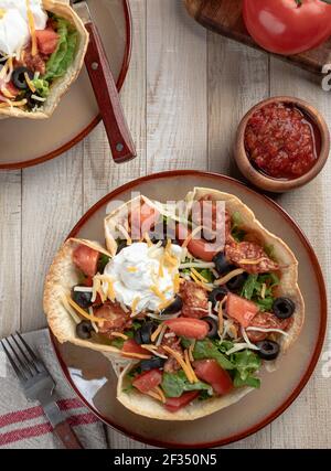 Vue en hauteur d'une salade de tacos faite avec du poulet, de la laitue, de la tomate, des olives noires, du fromage et de la crème sure dans une coquille de tortilla Banque D'Images