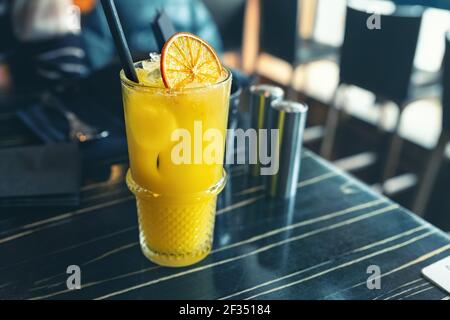 Verre avec un délicieux cocktail de limonade jaune vif aux agrumes et orange juteux sur une table en bois sombre au café ou au restaurant sur baugh matin ensoleillé Banque D'Images