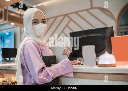 femme asiatique musulmane travaillant avec un pc tout en portant un visage médical masque Banque D'Images