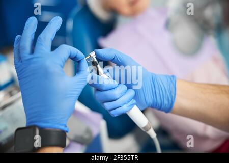 Mains dans des gants d'hôpital pour sortir le bur de la perceuse dentaire Banque D'Images