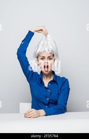 la femme prend la perruque blanche de la tête des émotions assis à boisson de table Banque D'Images