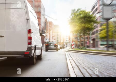 Minibus de livraison en ville au coucher du soleil Banque D'Images