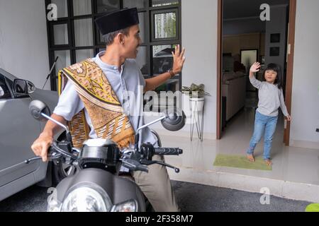 le père agite au revoir à son plus jeune à la maison avant départ à la mosquée Banque D'Images