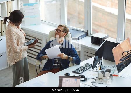 Portrait en grand angle de deux développeurs INFORMATIQUES discutant de projets tout en travaillant sur des applications logicielles et mobiles, bureau, espace de copie Banque D'Images